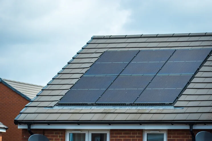 Solar panels on tiled roof of house, grey sky in background