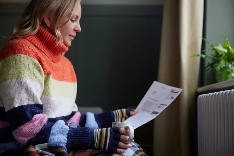 Cold woman looking at energy bills