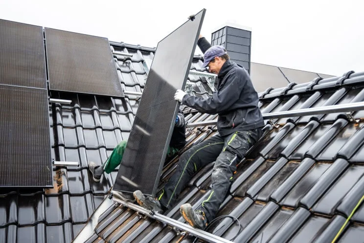 solar panel installers installing black solar panels on a grey roof