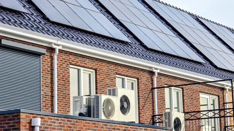 A row of houses with heat pumps and solar panels