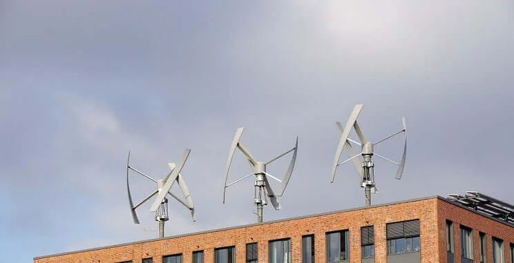 three small wind turbines on roof of urban red-brick building