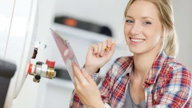 woman looks at camera as she's installing a boiler