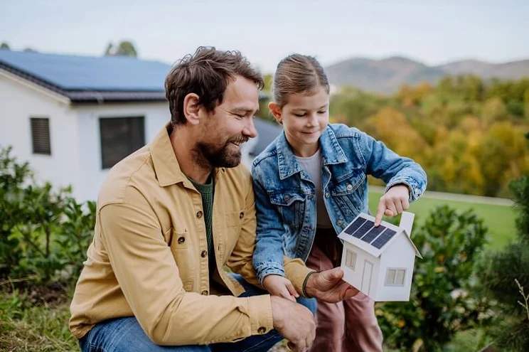 father and daughter looking at model house demonstrating sustainability