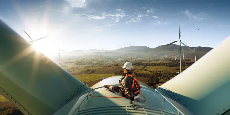 A person sitting on top of a wind turbine