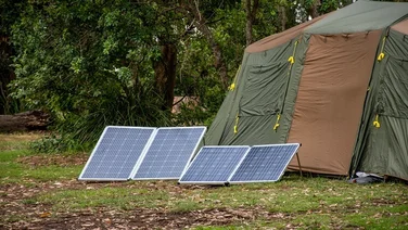Foldable solar panels propped up outside a large green tent