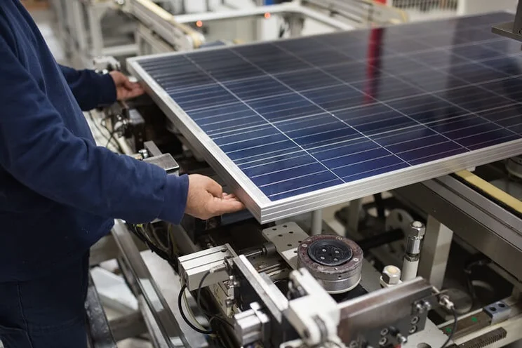 solar panel on manufacturing table being handled by a factory worker