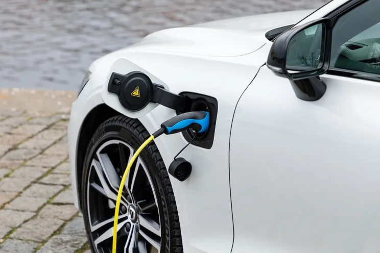 white electric car plugged in to charge
