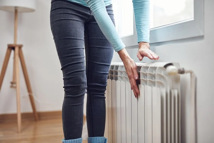 woman warming hand on radiator