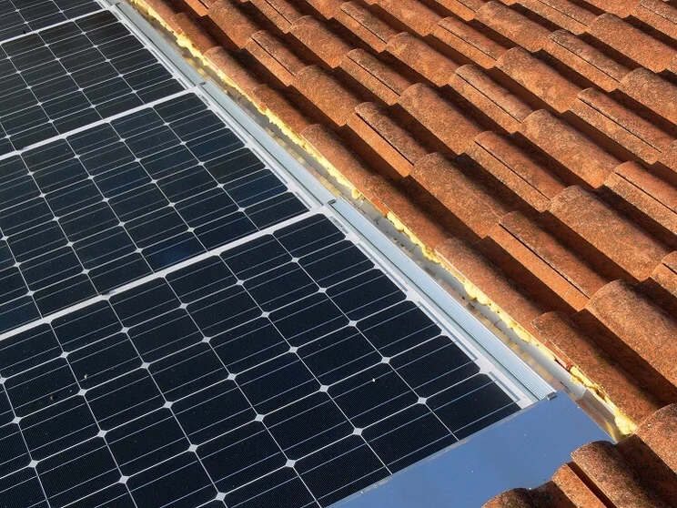 close up of monocrystalline solar panel on red tile roof