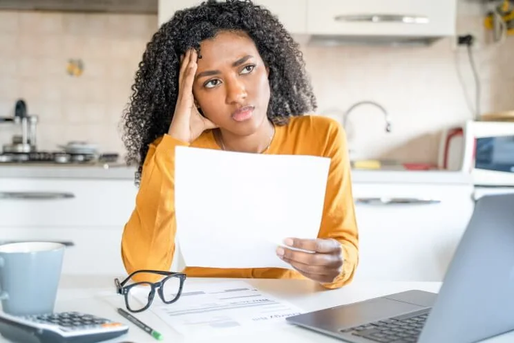 woman looking upset while holding a piece of paper