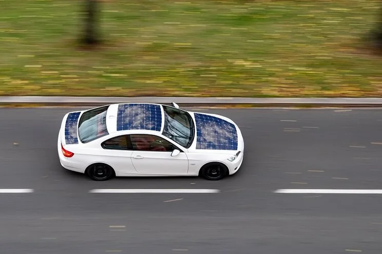 white car with built-in solar panels driving on road