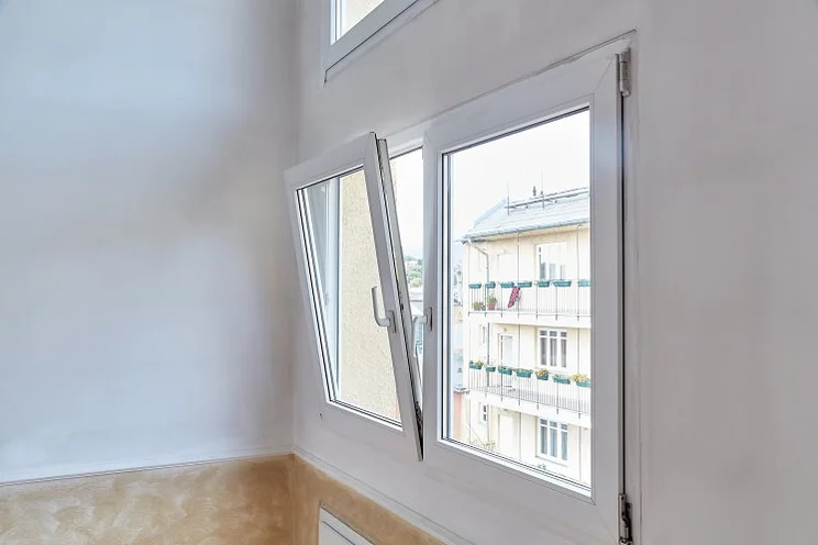 A large uPVC white tilt and turn window opening length ways in a white room with wooden floors