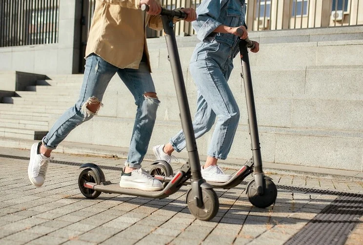 Two people riding electric scooters
