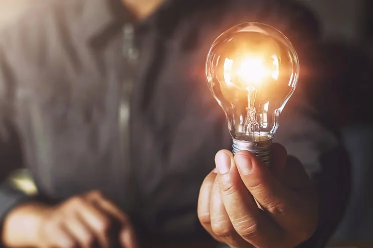 Person holding an illuminated halogen light bulb.