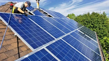 a man installs solar panels on a roof
