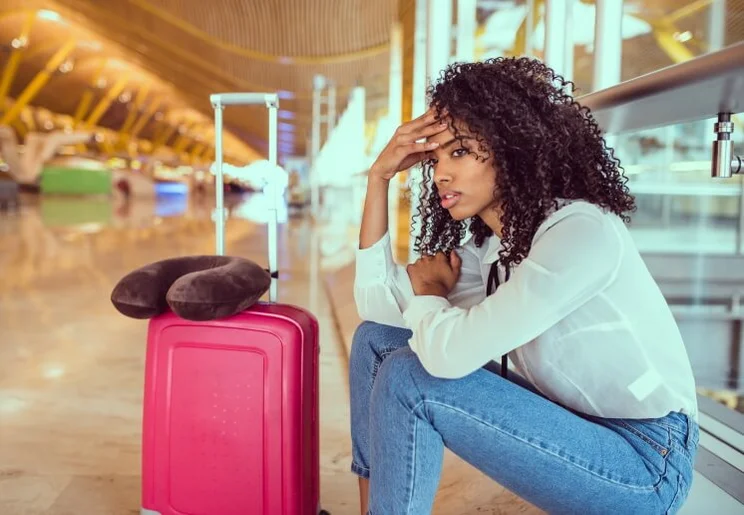 woman looking annoyed with her suitcase