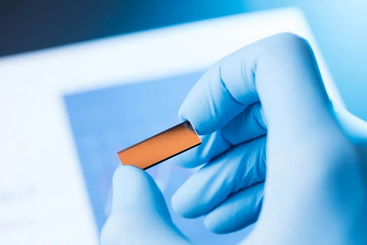 close up of solar cell being held by latex gloved hand