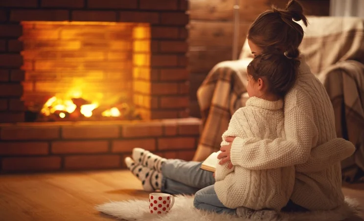 woman and child hugging in front of a fireplace