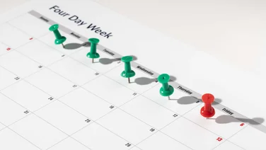 Printed calendar for a 4 day working week showing weekend days with red pins and weekdays with green pins