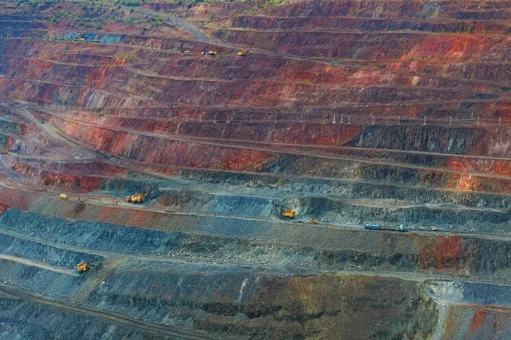 Large quarry with yellow trucks mining for iron ore