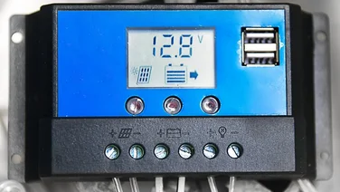 A blue and black solar charge controller showing figures on the digital screen