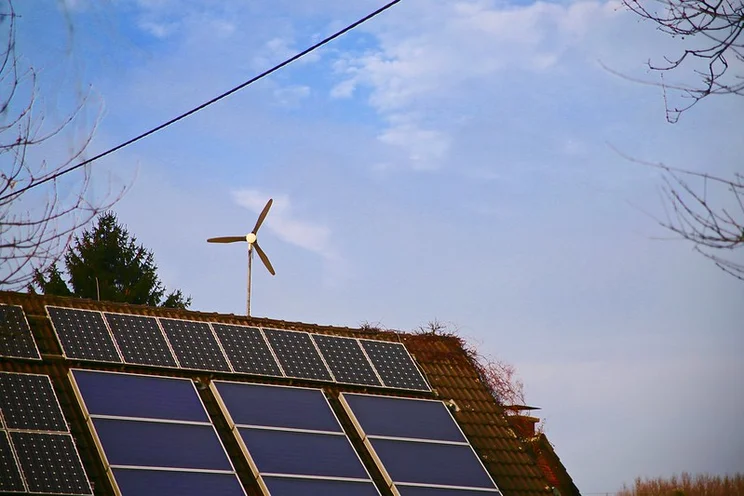 House with solar panels and wind turbine.