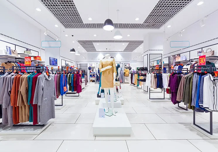 Interior of a clothes shop, with a white floor and ceiling, and a mannequin in the centre.