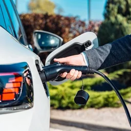 an arm plugging an electric vehicle charger into an electric vehicle