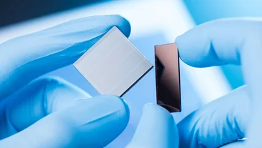 close up of solar cells in a lab bein held by gloved hands