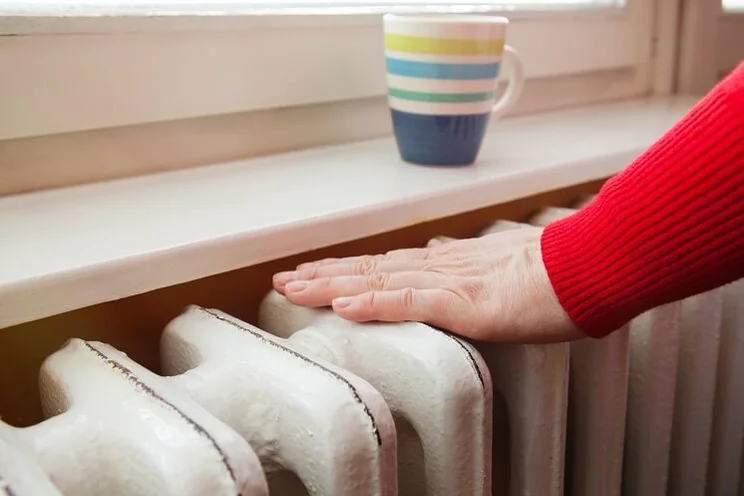 Person touches radiator to keep warm