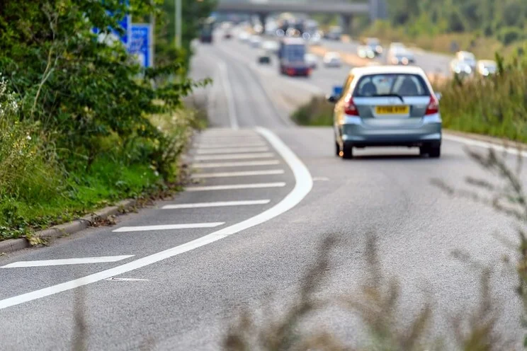 grey car driving down turn in highway