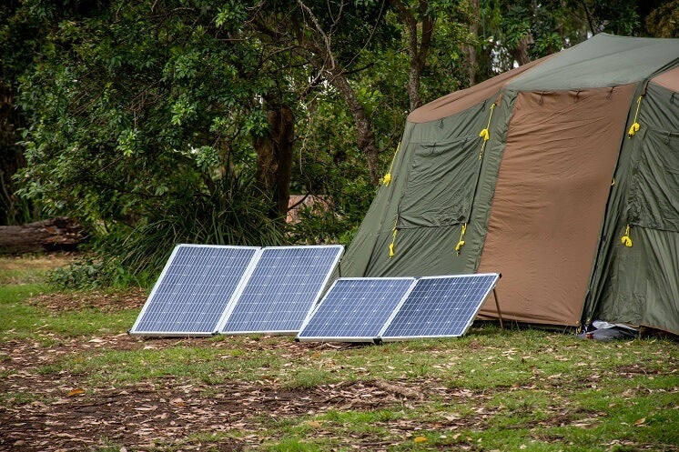 Foldable solar panels propped up outside a large green tent