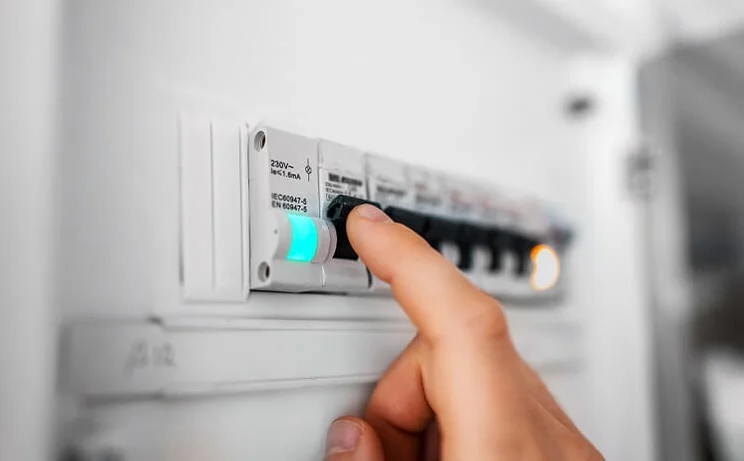 man's hand flipping switch on electricity switchboard