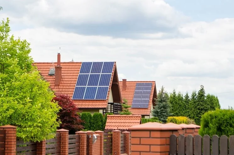 A couple of houses sat parallel to each other with red tiled roofs and blue solar panels