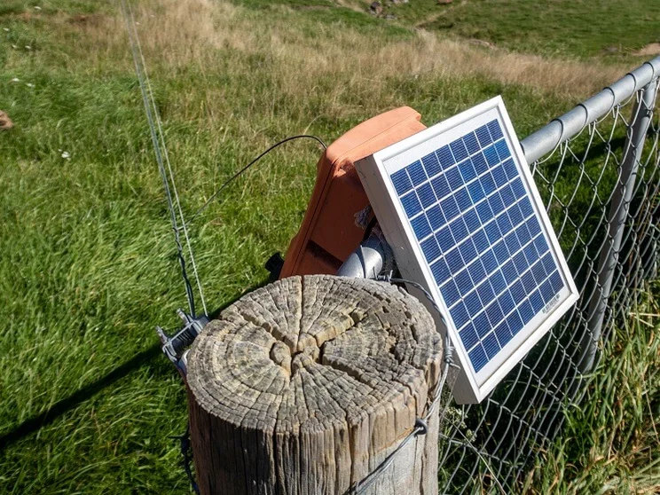 solar panel on mesh fence next to wooden pole