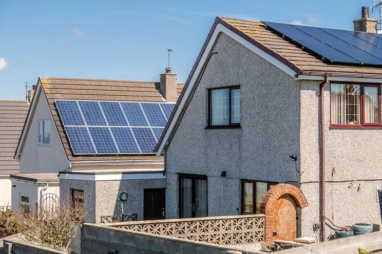 Roof Mounted Solar Panels in Holyhead, Wales. There is a clear blue sky in the background.