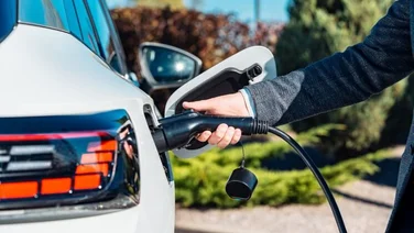an arm plugging an electric vehicle charger into an electric vehicle