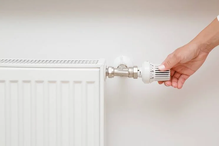 person adjusting radiator thermostat