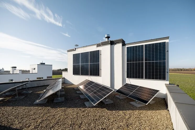 Eight square dark solar panels lying vertically on a white wall
