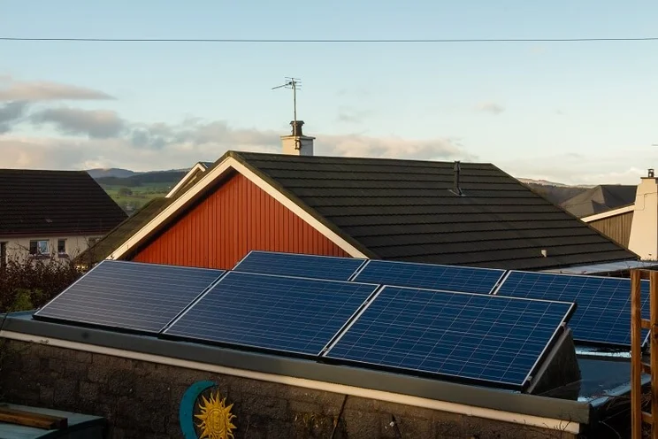 Pitched solar panels on a flat roof on a property in the UK, at sunrise
