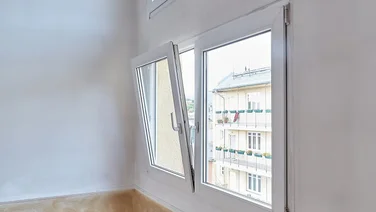 A large uPVC white tilt and turn window opening length ways in a white room with wooden floors