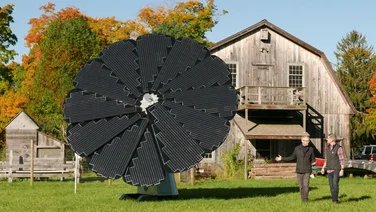 A SmartFlower installed on a field outside a barn