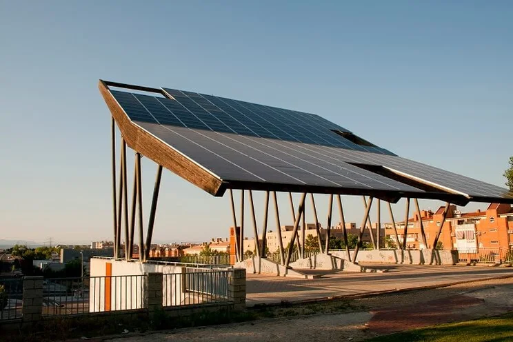 solar panel pergola above parking lot, with urban dwellings in background