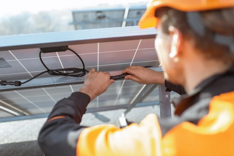 a solar engineer holds a solar panel's wires
