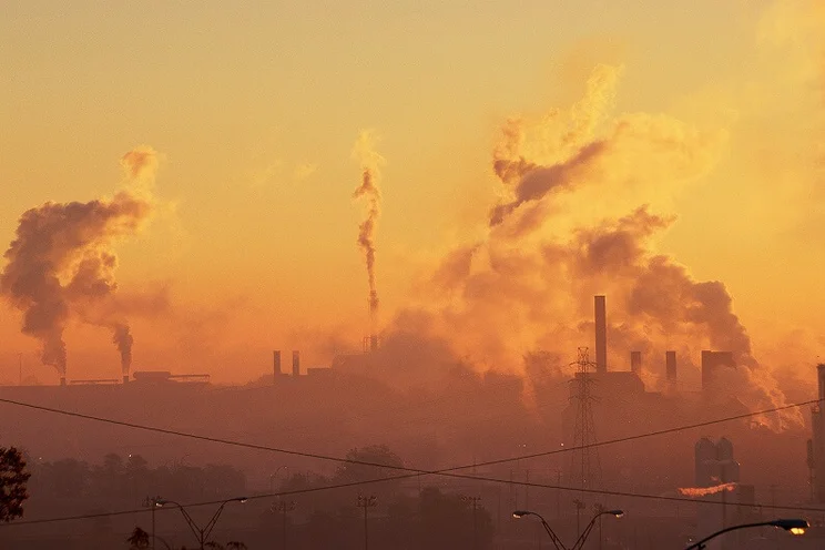 Dawn light with heavy industry in the background, there is thick smog billowing out of factories