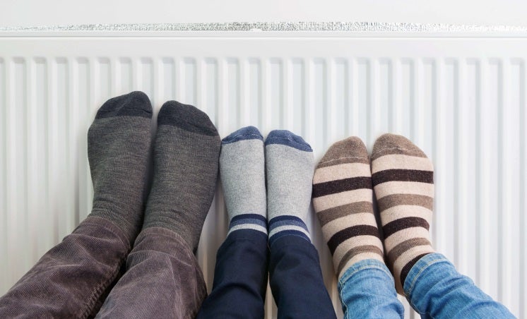 Three people put their feet on a radiator powered through a boiler