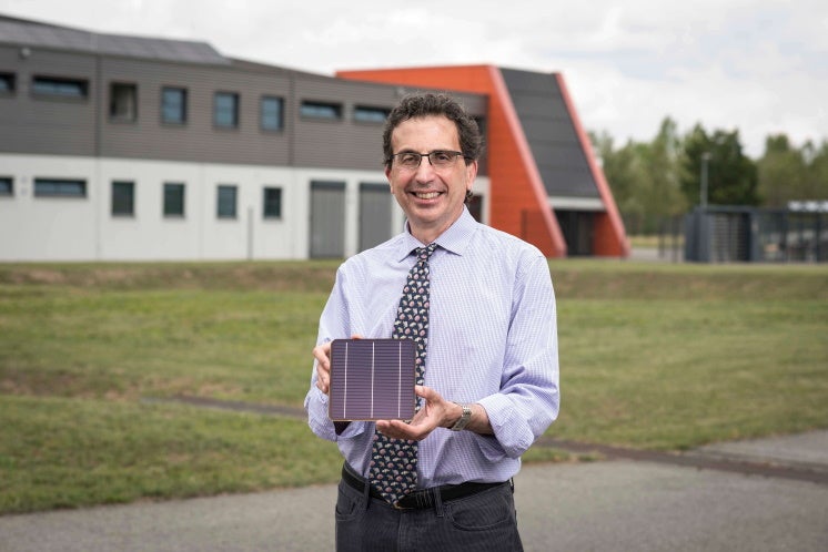 Dr Chris Case outside Oxford PV's German factory, holding a perovskite tandem solar cell
