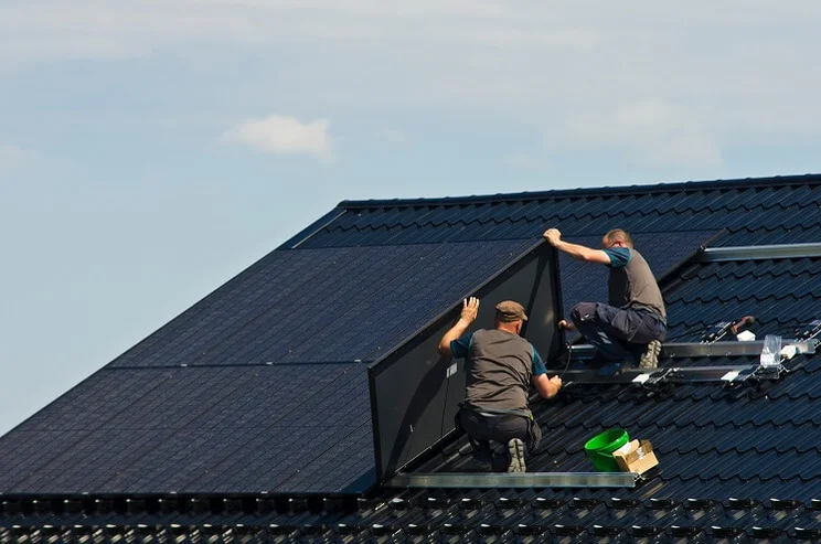 Two solar panel installers on a roof