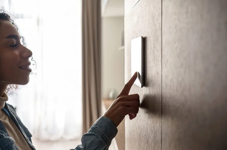 Woman turning thermostat on