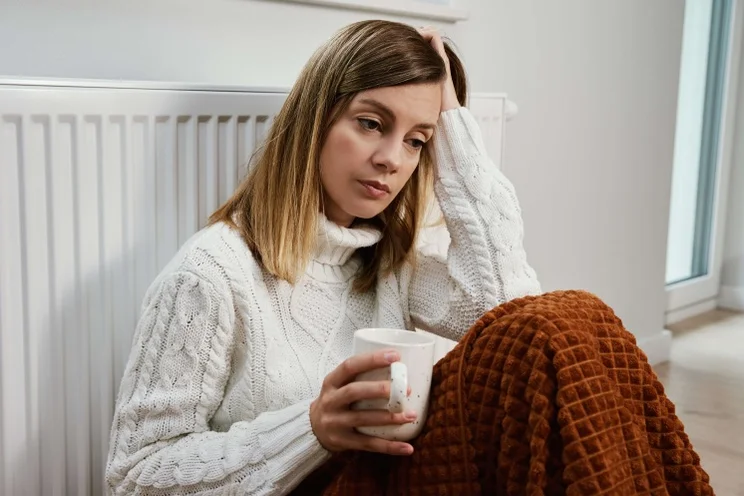 woman sits next to a radiator